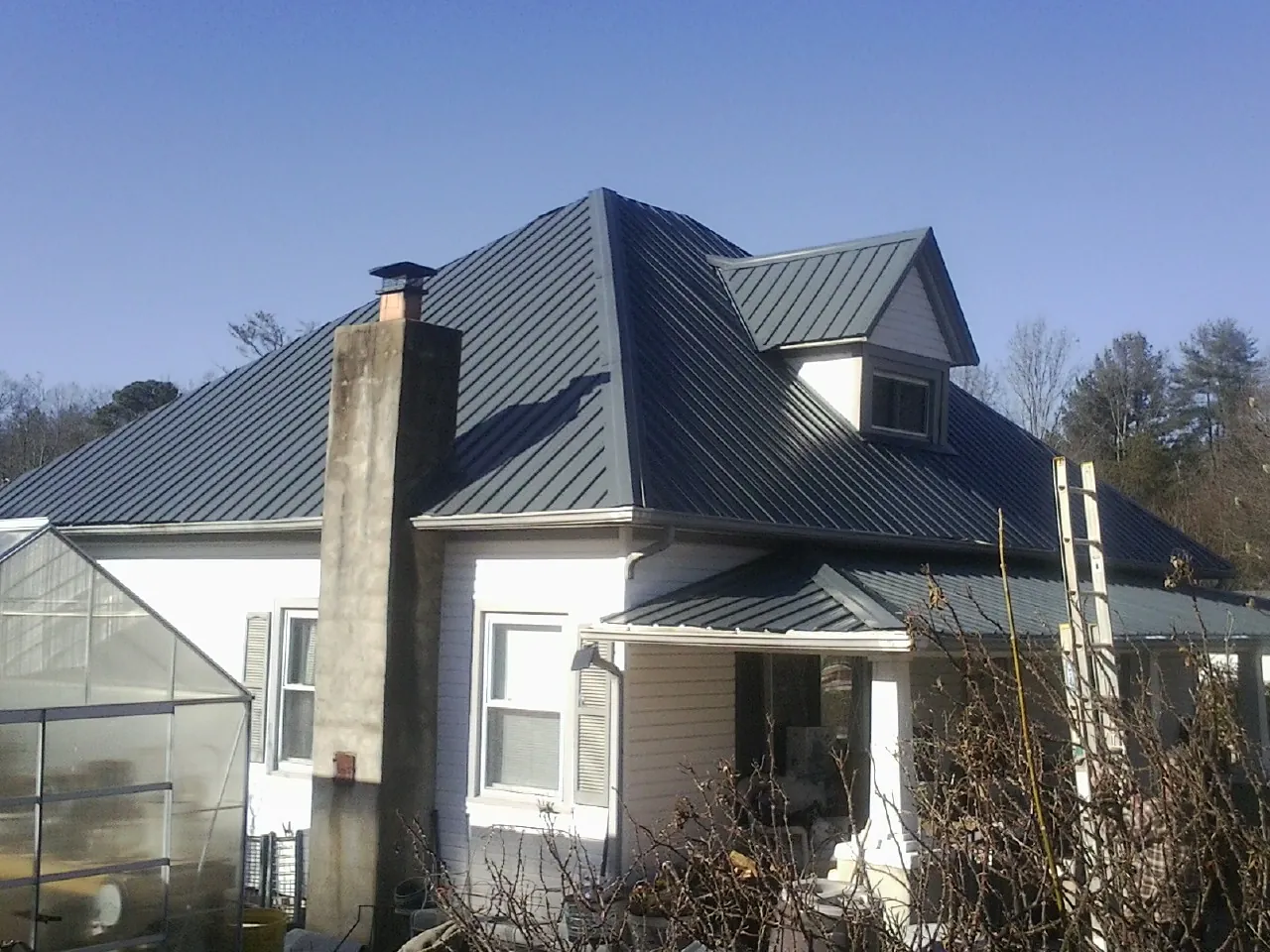 Dark blue standing seam metal roof on a white farmhouse with dormer — Slate & Tile Roof Repair by Roofing Brothers in La Mesa